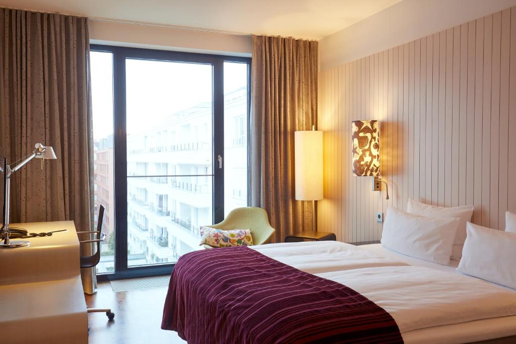 a hotel room with a bed and a large window at Scandic Berlin Potsdamer Platz in Berlin