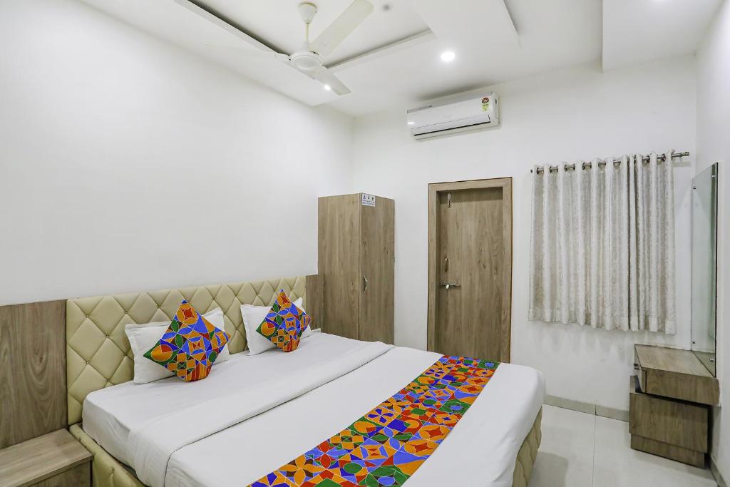 a bedroom with a large white bed with colorful pillows at FabHotel Angeethi in Aurangabad