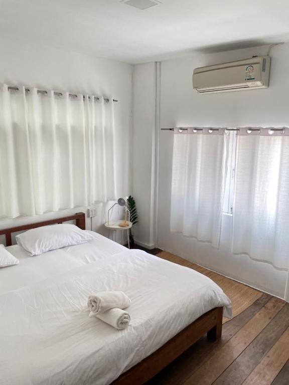 Cette chambre comprend un lit avec des draps blancs et un ventilateur. dans l'établissement Le Moon Hotel, à Chiang Khan