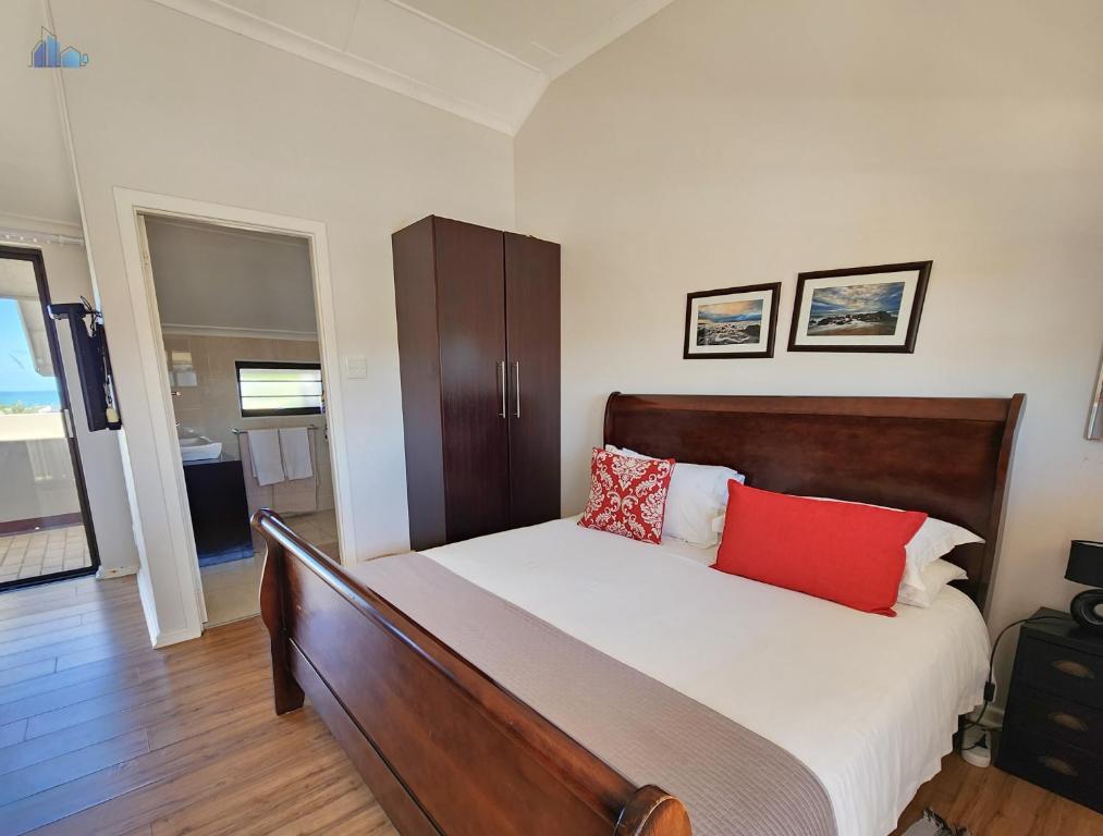 a bedroom with a bed with red pillows on it at Gonubie Guest Cottages in East London