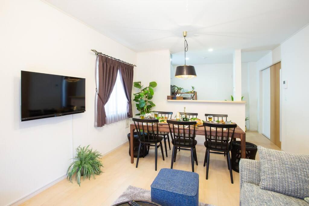 a dining room and living room with a table and chairs at シンプルでおしゃれなインテリアが光る4LDKの一軒家まるまる貸し切り！最大12名まで宿泊可能！ in Tokeshi
