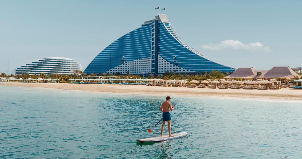 un hombre parado en una tabla de surf de remo en el agua en Jumeirah Beach Hotel Dubai, en Dubái