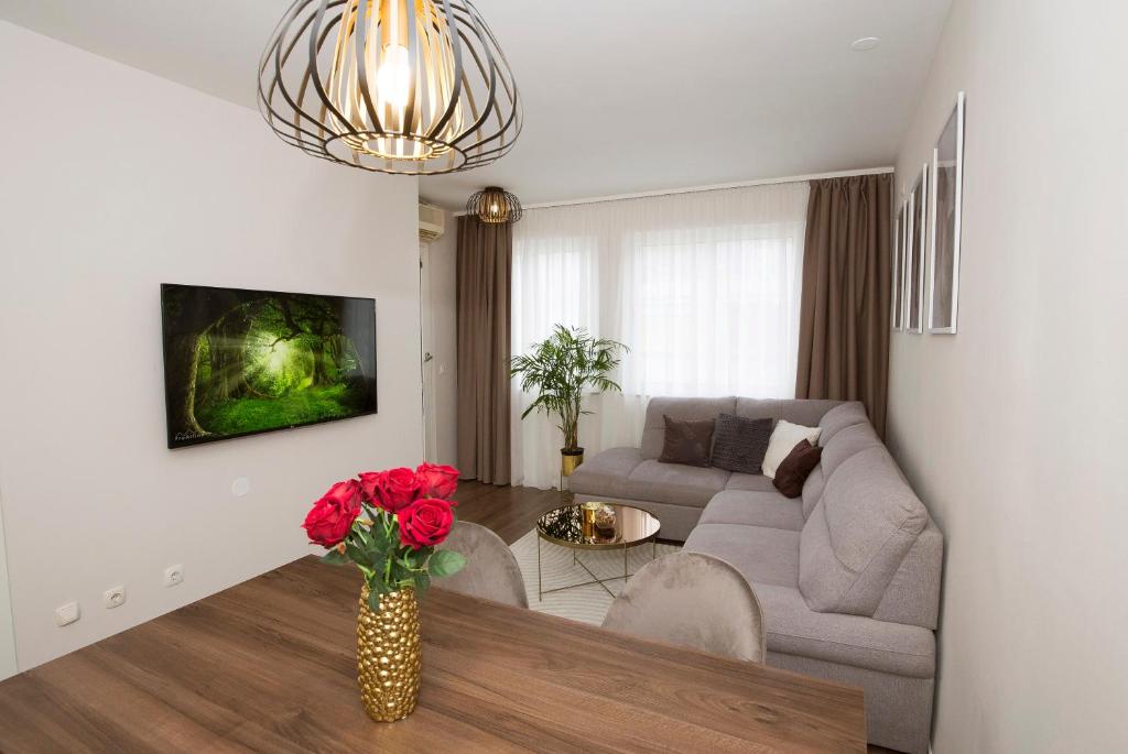 een woonkamer met een bank en een vaas met rode rozen bij Cosy apartment near city centar and sea- Marina, Omiš in Omiš