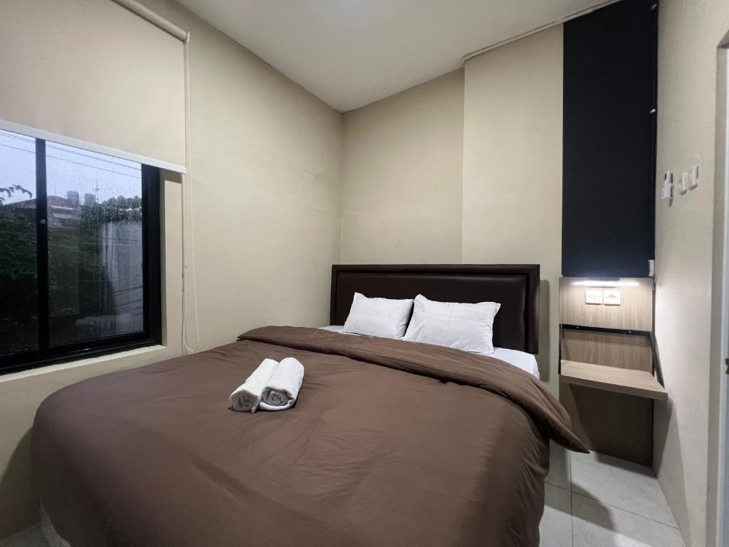 - une chambre dotée d'un lit avec une paire de chaussures dans l'établissement Brenn Hotel Semarang Mitra Reddoorz, à Semarang