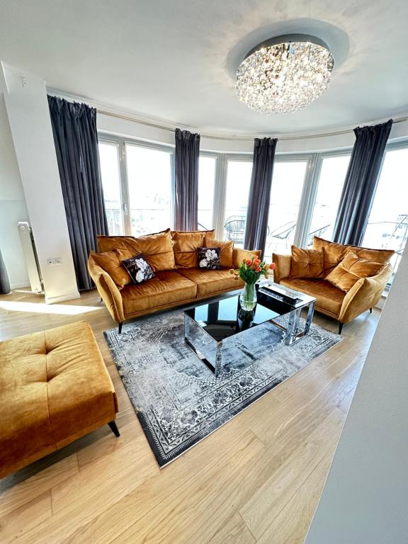 a living room with leather furniture and a chandelier at LUXURIOUS APARTMENTS Cracow in Krakow