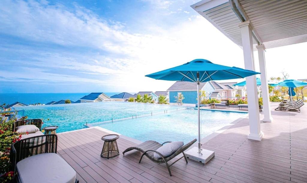 a swimming pool with chairs and an umbrella at Villa 028 - Villa Novaworld Phan Thiet View Biển - 4BR - 3 Toilet in Phan Thiet