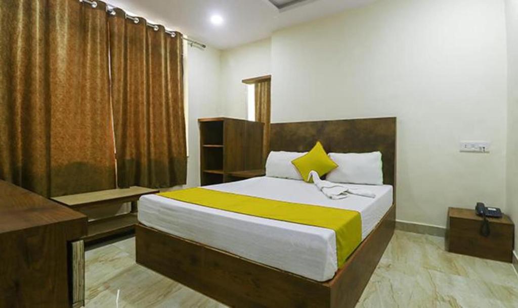 a bedroom with a large bed with yellow and white sheets at FabHotel Rama Inn I in Gwalior