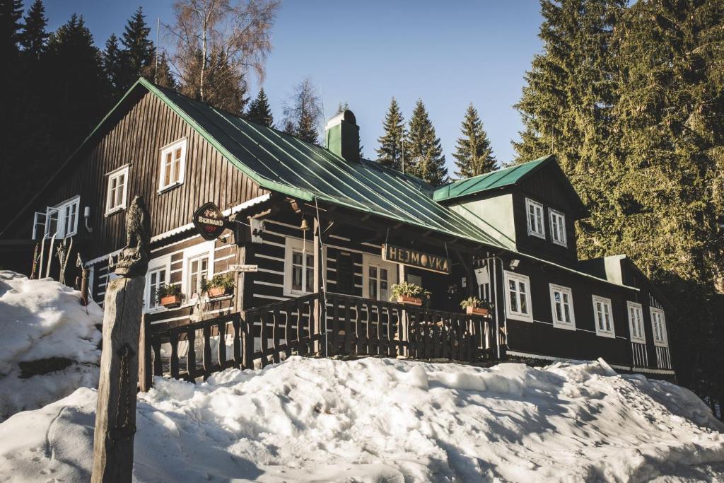 une grande maison en bois avec de la neige devant elle dans l'établissement Chalupa Hejmovka, à Špindlerův Mlýn