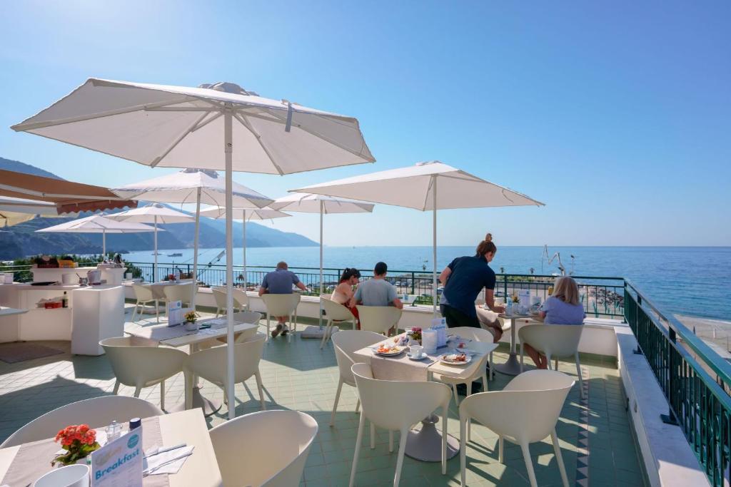 a group of people sitting at tables with umbrellas at Villa degli Argentieri in Monterosso al Mare