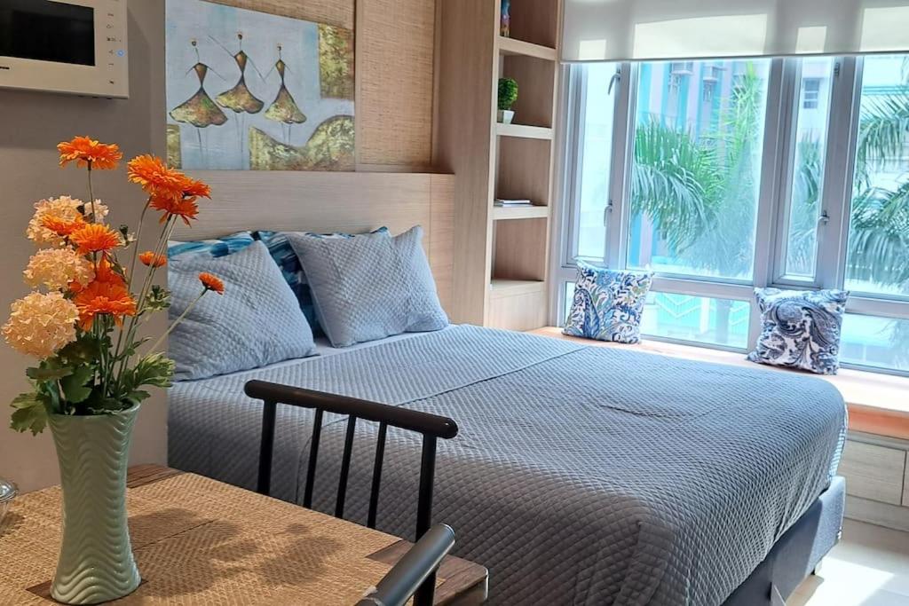 a bedroom with a bed and a vase of flowers at Lovely Condo near NAIA T3 in Manila