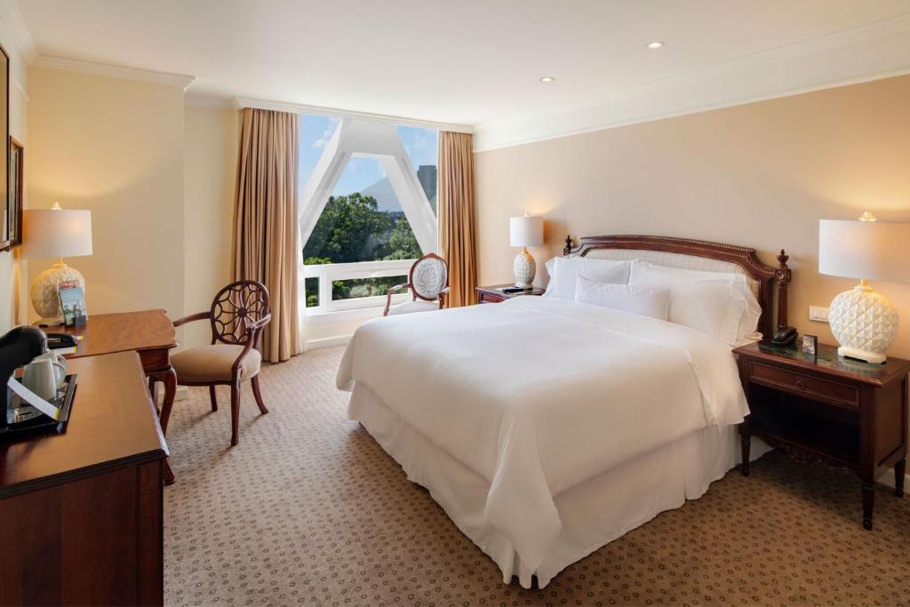 Un dormitorio con una gran cama blanca y una ventana en The Westin Camino Real, Guatemala, en Guatemala