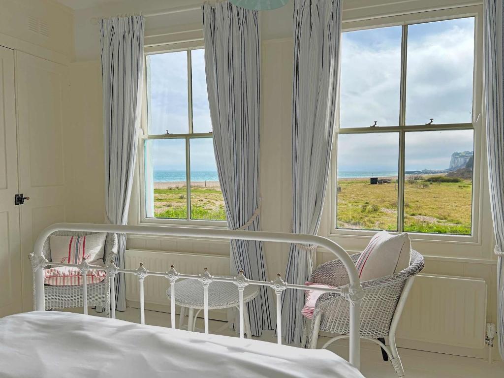um quarto com uma cama, 2 cadeiras e uma janela em Boho-chic bolthole on the beach - Mariner's Cottage em Deal