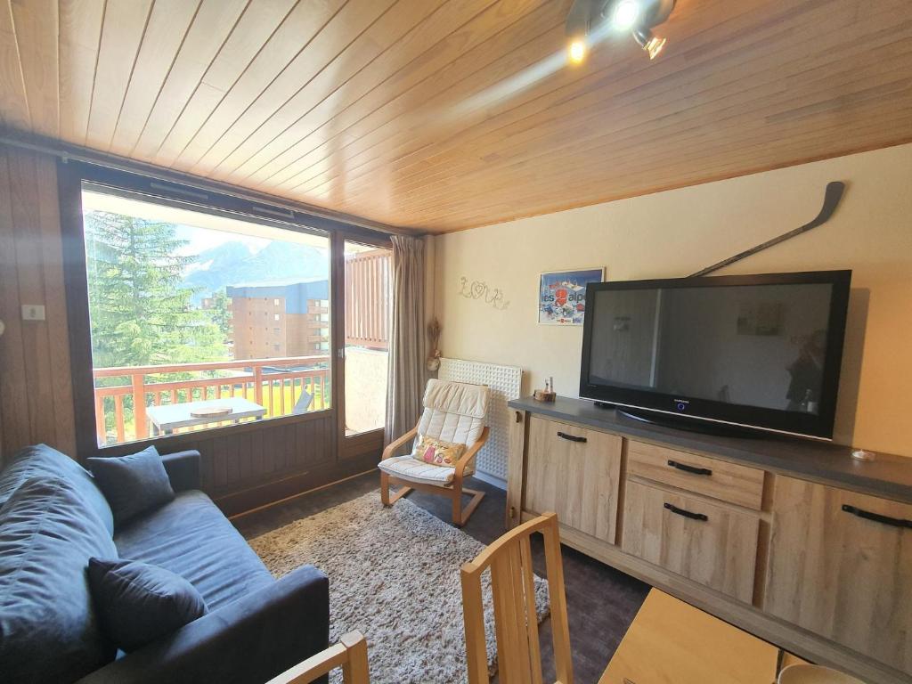 sala de estar con sofá azul y TV de pantalla plana en Meijotel - 45 - Studio centre- 6 pers en Les Deux Alpes