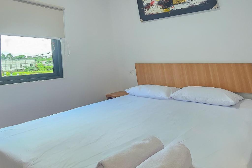 a bedroom with a large white bed with a window at Hotel Buana Express RedPartner in Bojonegoro