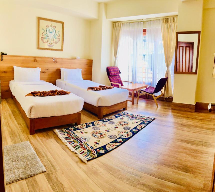 a hotel room with two beds and a rug at Hotal Khuruu Khuruu in Pajo