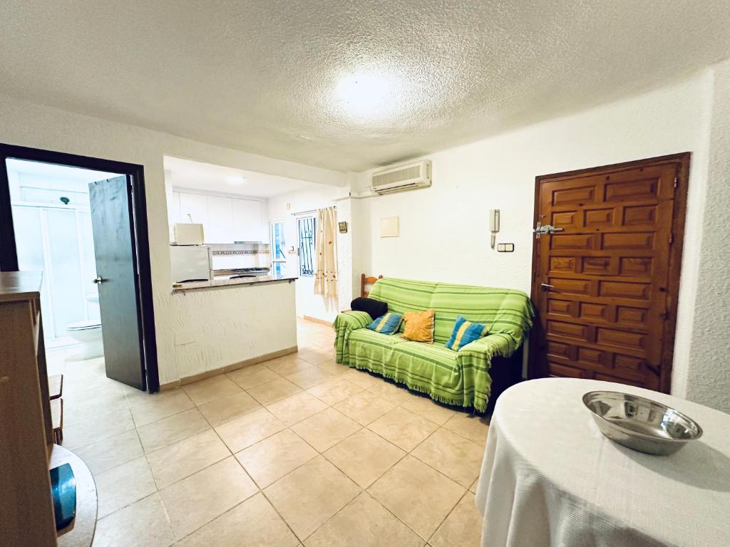 ein Wohnzimmer mit einem grünen Sofa und einer Küche in der Unterkunft 2 dormitorios 95 m de la playa in Los Alcázares