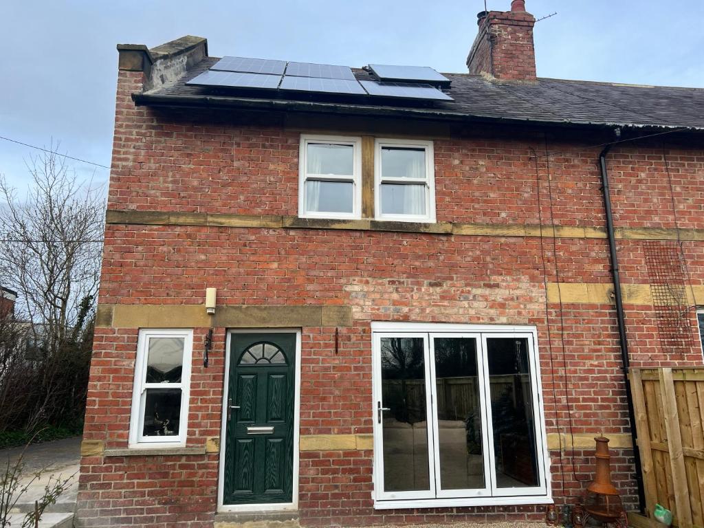 a red brick house with solar panels on the roof at Morpeth, Northumberland home in Morpeth