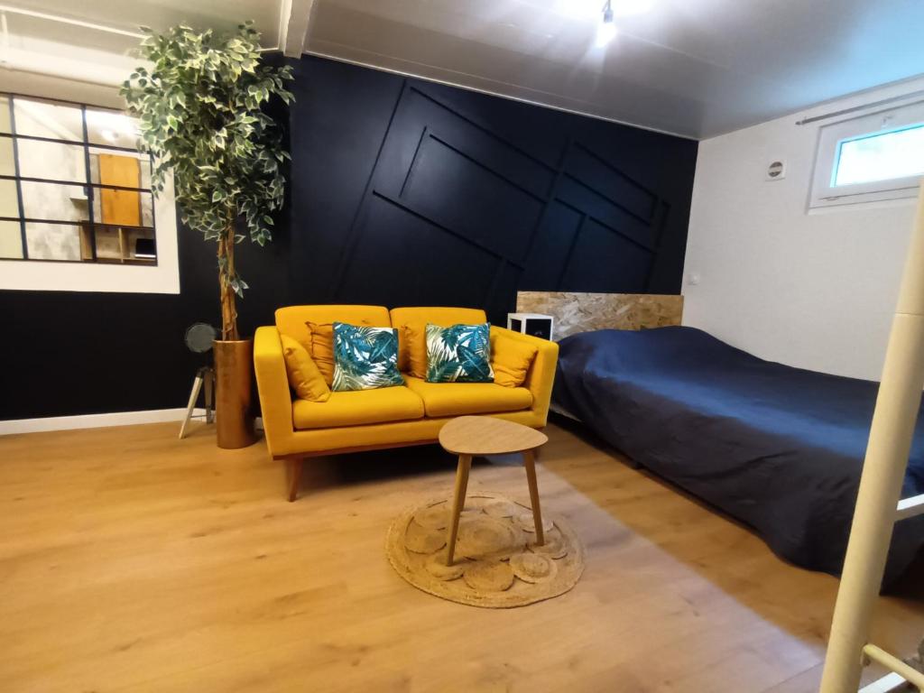 sala de estar con sofá amarillo y cama en Appartement tout confort, en Le Fresne-Camilly