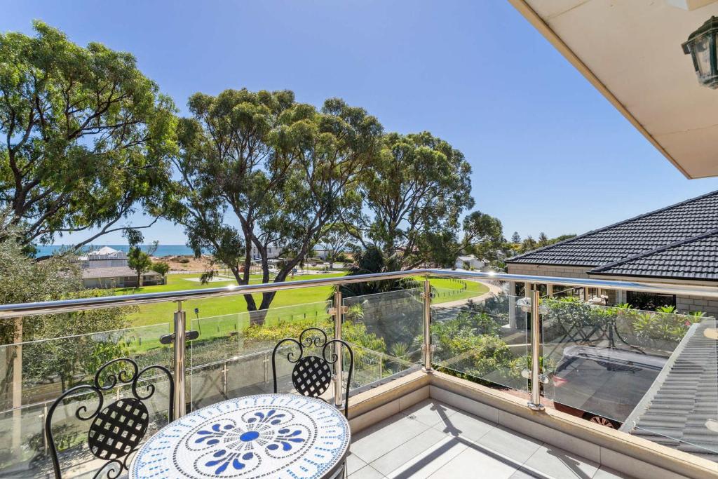 a balcony with a table and chairs and trees at Silver Sands Holiday & Beach House in Mandurah