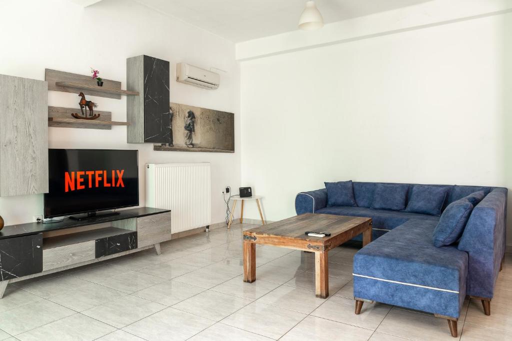 un salon avec un canapé bleu et une télévision dans l'établissement King home Larissa city, à Larissa