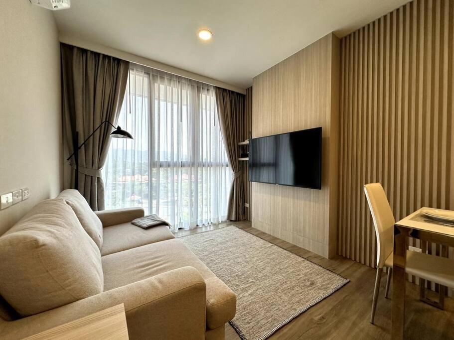 een woonkamer met een bank en een flatscreen-tv bij 2 Bedroom Skypark Condo Laguna in Bang Tao Beach