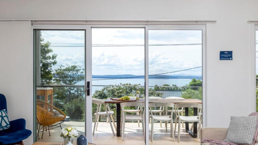 een woonkamer met een tafel en stoelen en uitzicht op de oceaan bij Embracing Dutchies in Nelson Bay