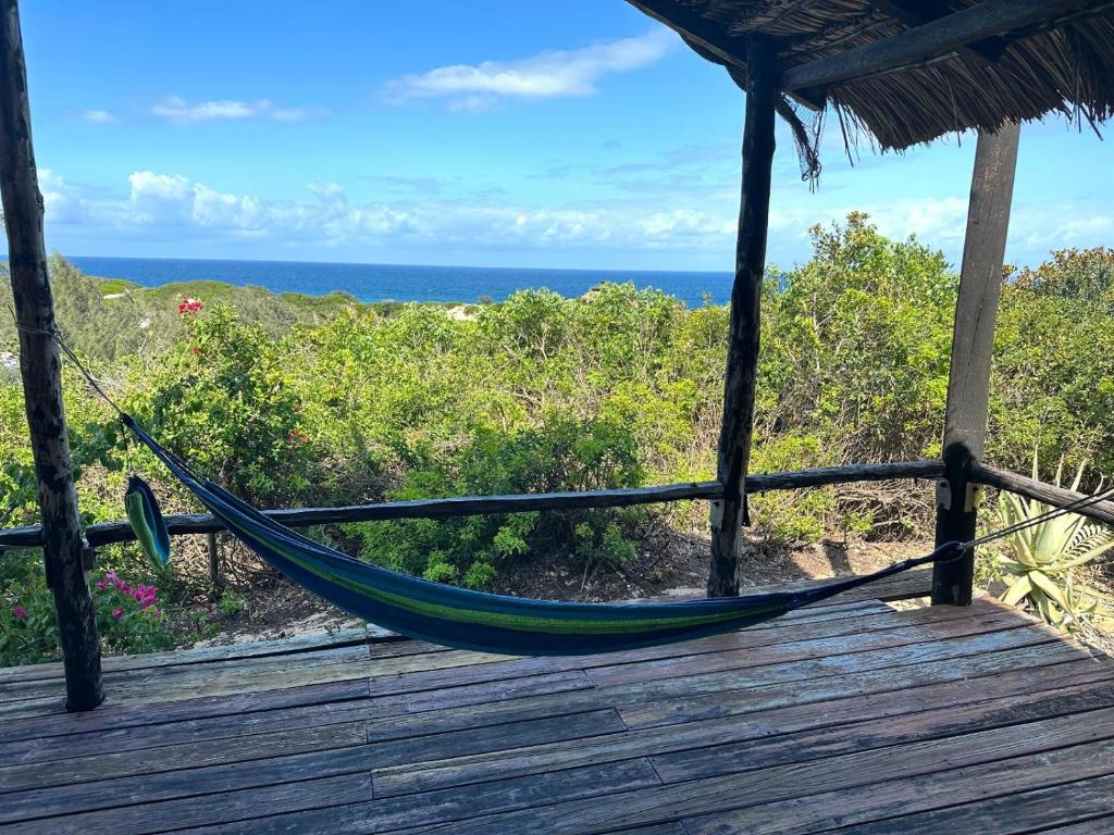 a hammock on a deck with the ocean in the background at Paradise Dunes in Praia do Tofo