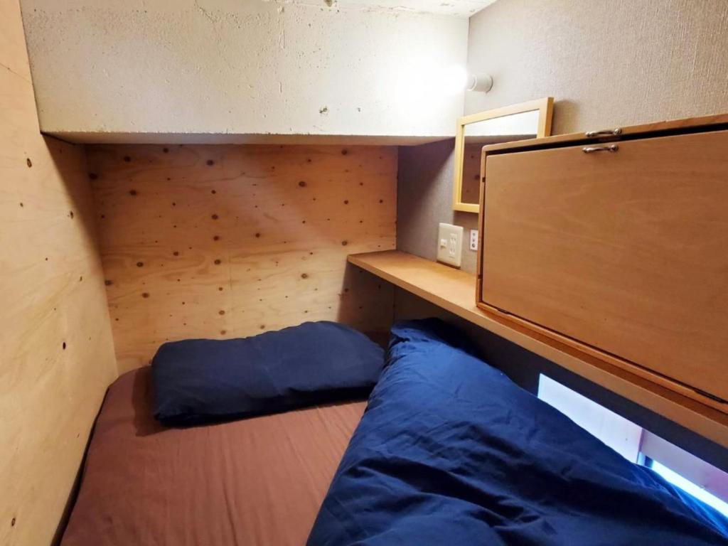 Habitación pequeña con cama y pared de madera. en ゲストハウス EZO Run Sapporo 札幌中心部でシンプルな滞在ができるホステル, en Sapporo