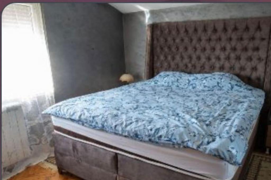 - un lit avec une couette bleue dans une chambre dans l'établissement Vila Marija, à Podgorica