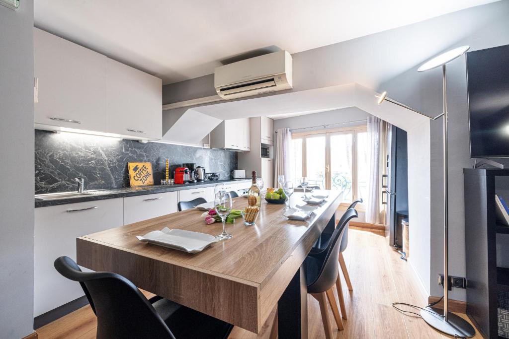 une cuisine avec une grande table et des chaises en bois dans l'établissement 3 pièces des Jardins parking clim 1 min plage, à Menton