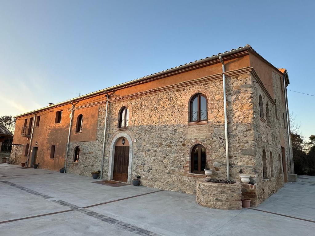 an old stone building with a large building at El Molí de Fornells in Fornells de la Selva