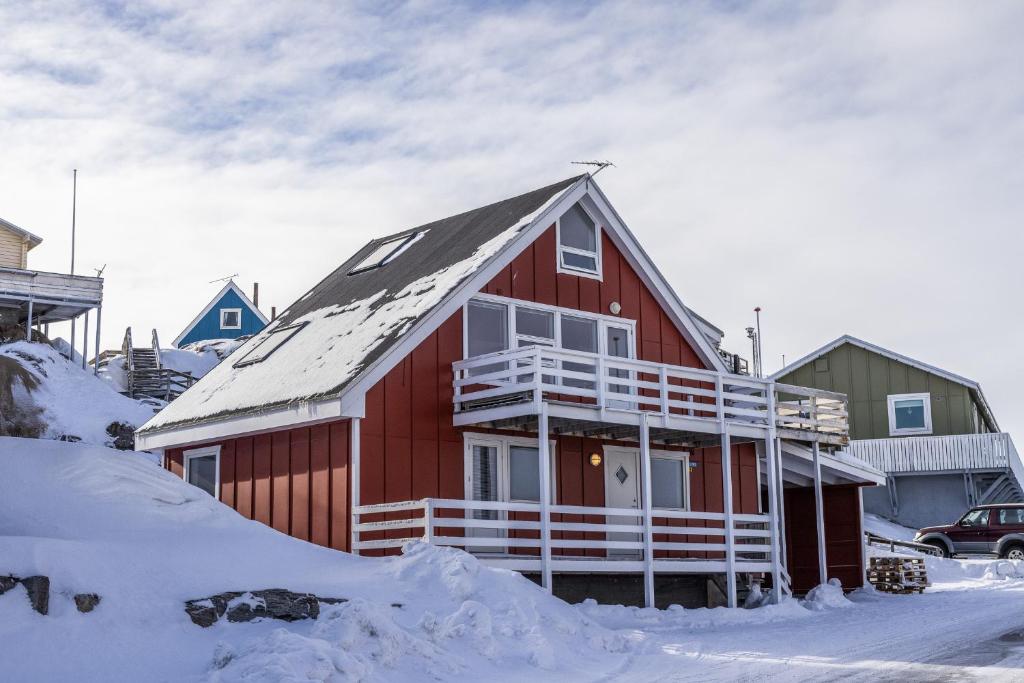 una casa roja con nieve en el techo en 4-bedroom house with sea view and hot tub en Ilulissat