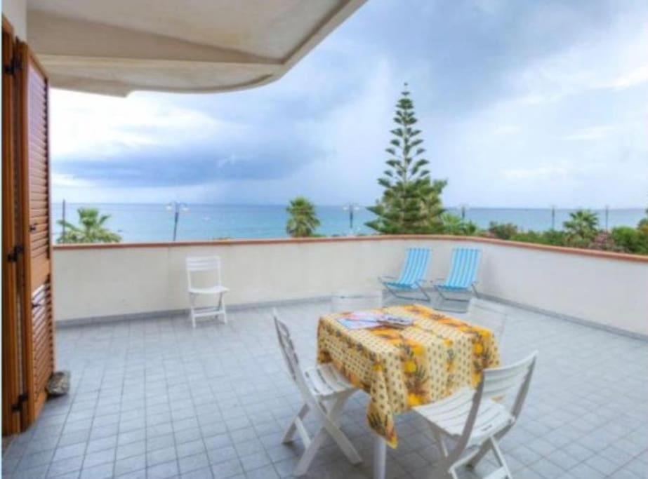 a patio with a table and chairs on a balcony at appartamento sul mare in Falcone