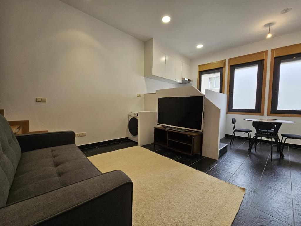 uma sala de estar com um sofá e uma televisão de ecrã plano em Magnifico apartamento en Canelas em Portonovo