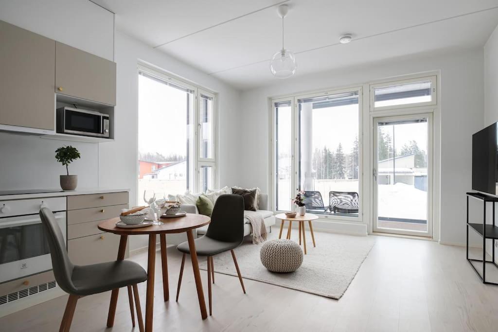 a white living room with a table and chairs at LadyCrane apartment, sauna and parking in Kirkkonummi