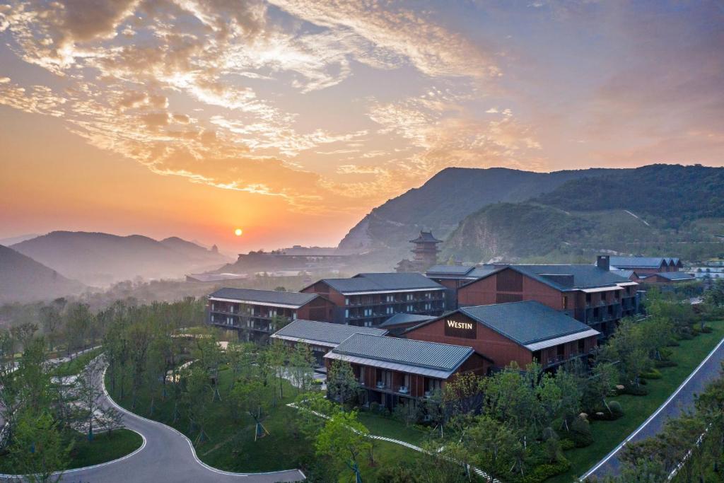 ein Dorf in den Bergen mit Sonnenuntergang im Hintergrund in der Unterkunft The Westin Nanjing Resort & Spa in Nanjing
