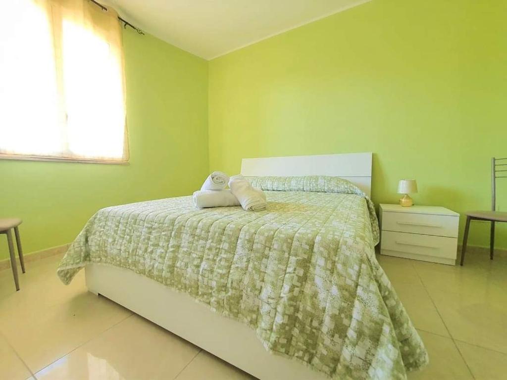 1 dormitorio verde con 1 cama con 2 almohadas en Appartamento con tutti i confort, en Castro di Lecce