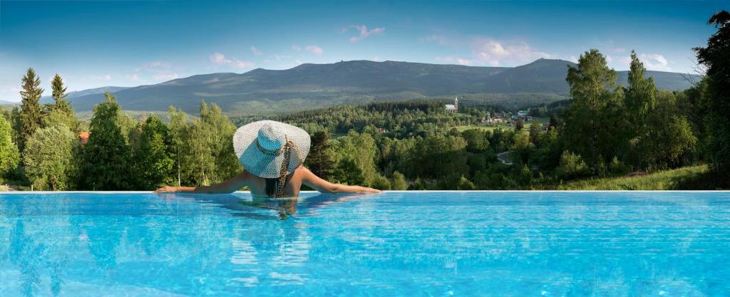 a person sitting on the edge of a swimming pool at Happy Valley Resort Szklarska Poręba in Szklarska Poręba