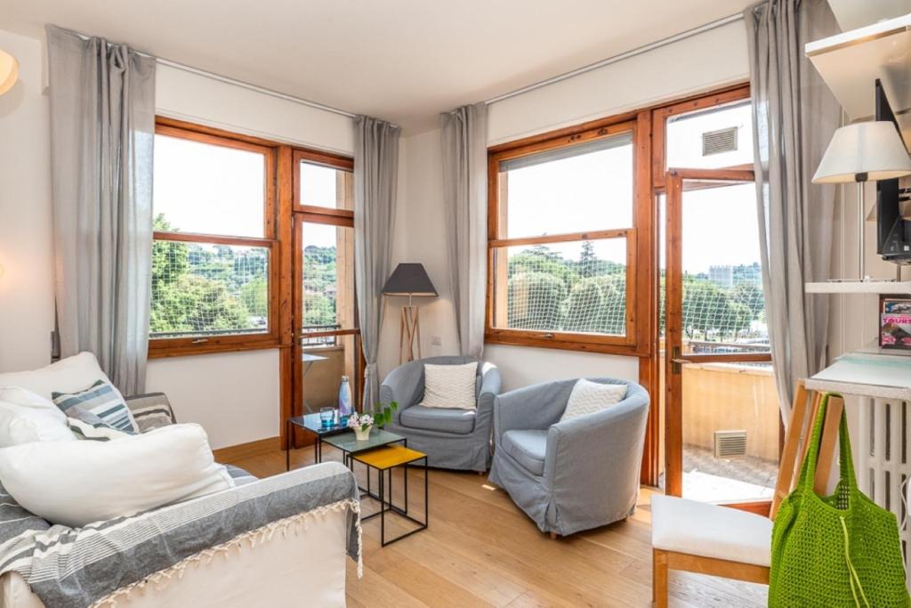 a living room with a couch and chairs and windows at Lungarno del Tempio River View by 360Rentals in Florence