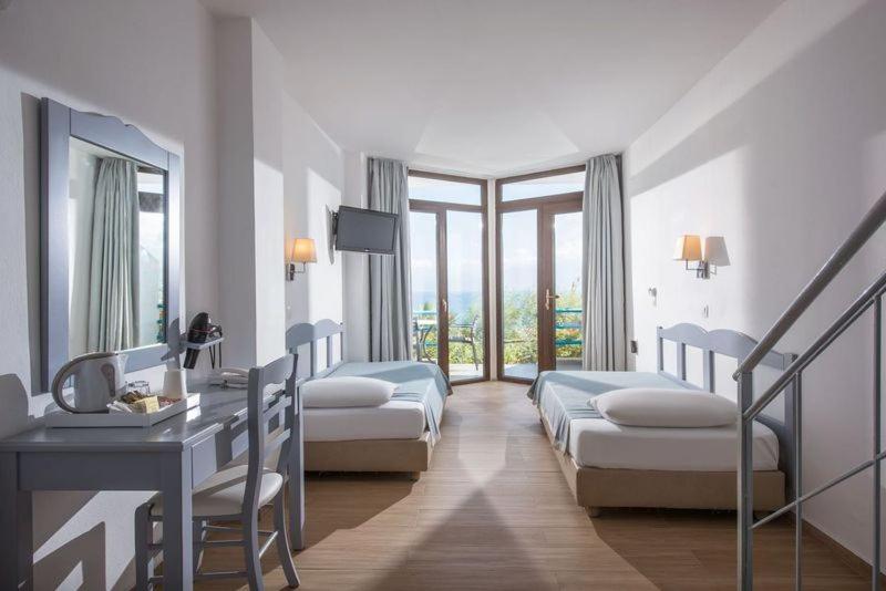 Cette chambre comprend 3 lits et un bureau. dans l'établissement Hersonissos Village Hotel & Bungalows, à Chersónissos