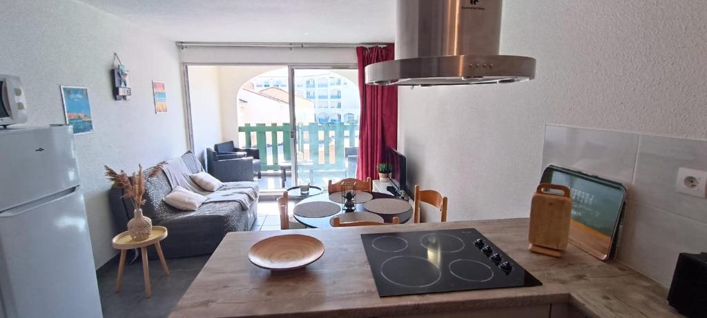 Il dispose d'une cuisine et d'un salon avec une table et un réfrigérateur. dans l'établissement Bel appartement au pied du marché noel, au Barcarès