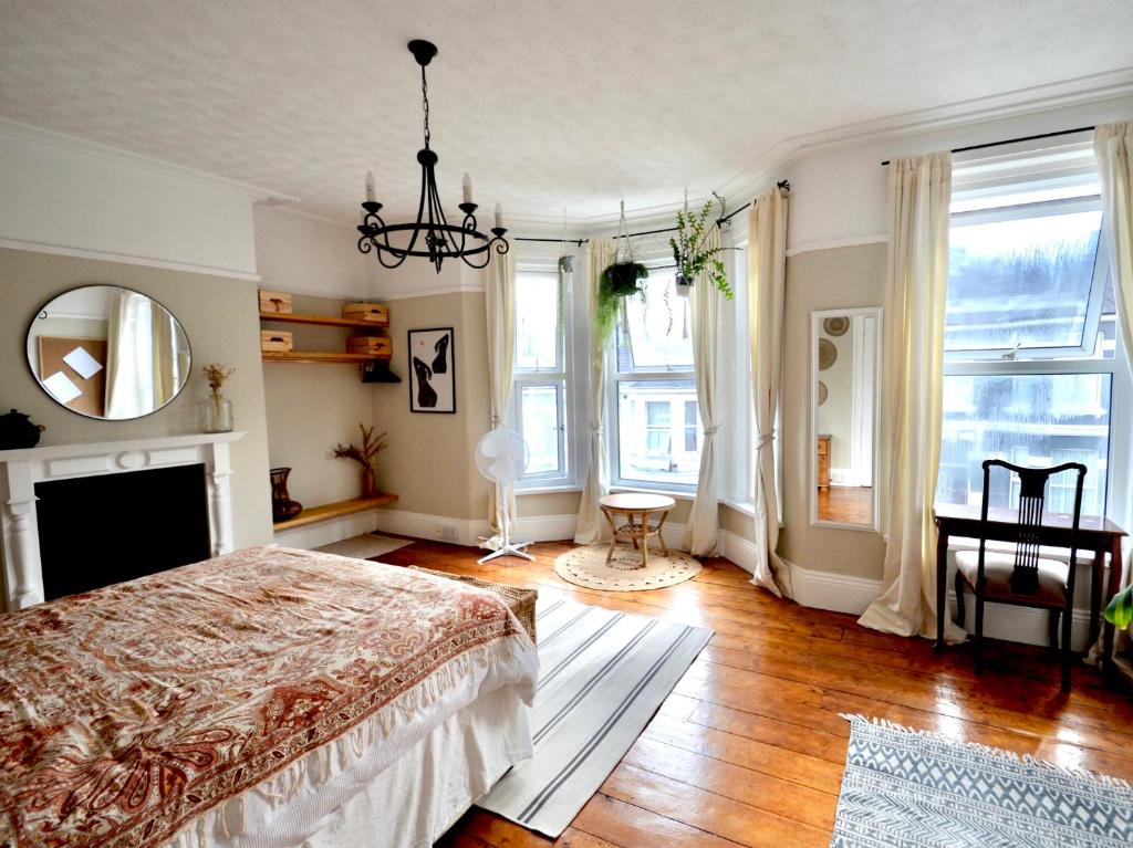 een slaapkamer met een bed, een spiegel en ramen bij Bright and cosy, central 3 bedroom home in Plymouth
