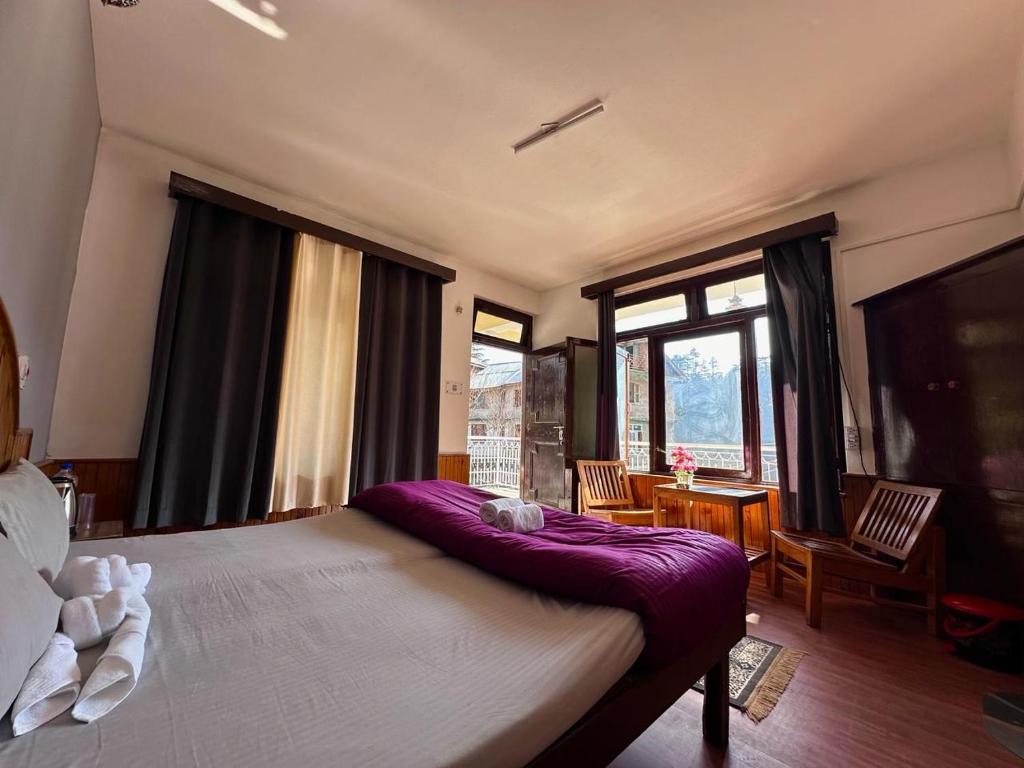 una camera da letto con un grande letto con una coperta viola di Beholden Stay and Cafe a Manāli