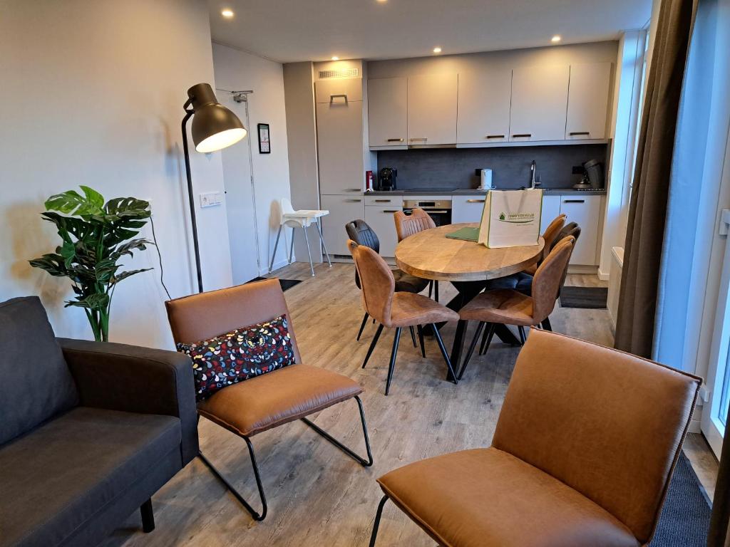 een woonkamer met een tafel en stoelen en een keuken bij 107,5 Nieuw appartement met sauna in Westkapelle