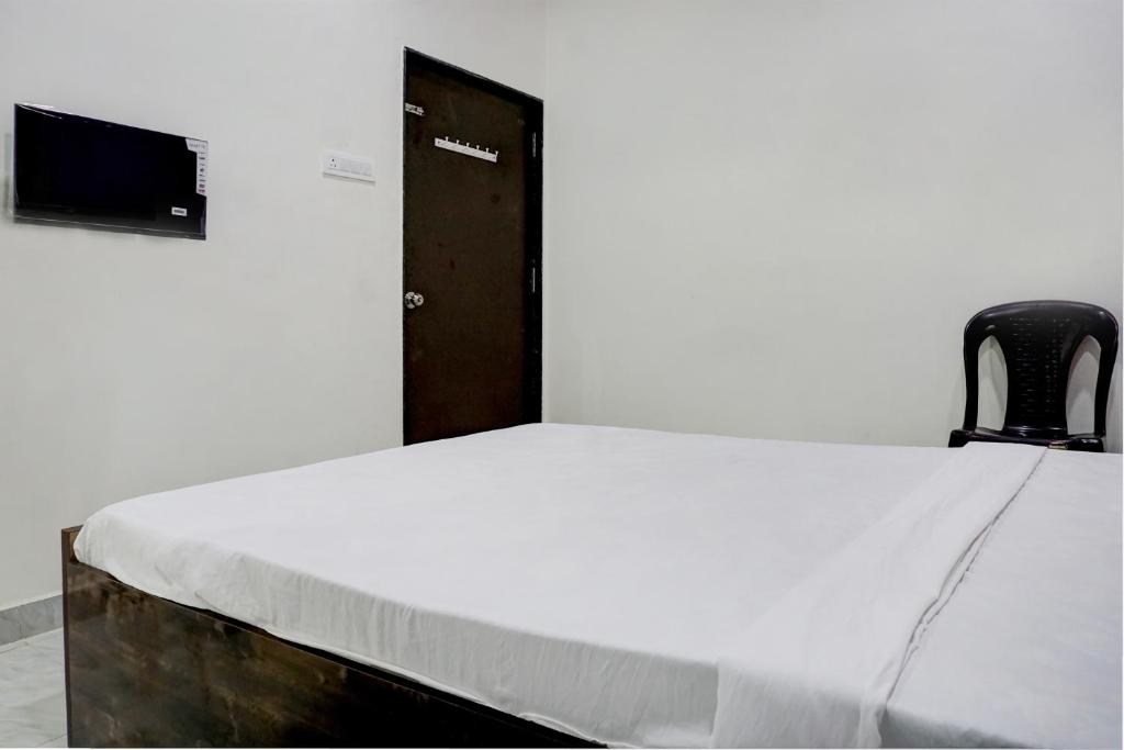 a bed in a room with a black chair at Hotel Mango Tree Lodging in Pune