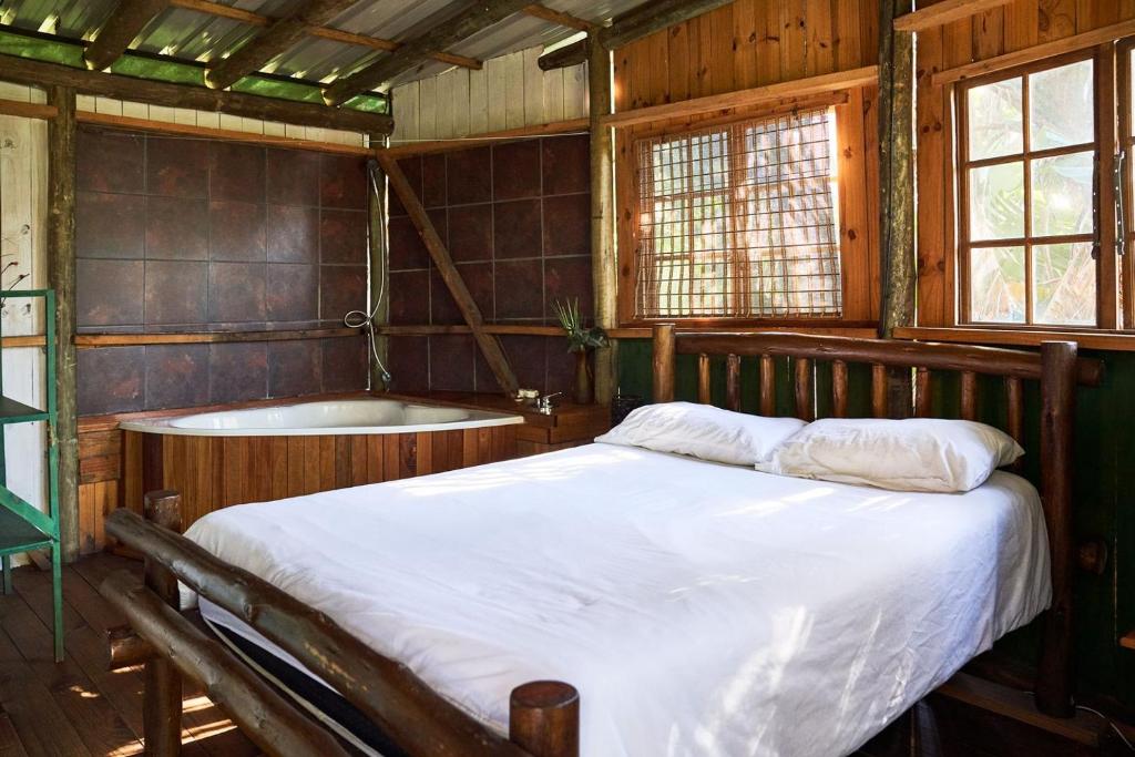1 dormitorio con cama y bañera en Mantis and Moon Backpackers and Surf Hostel en Hibberdene