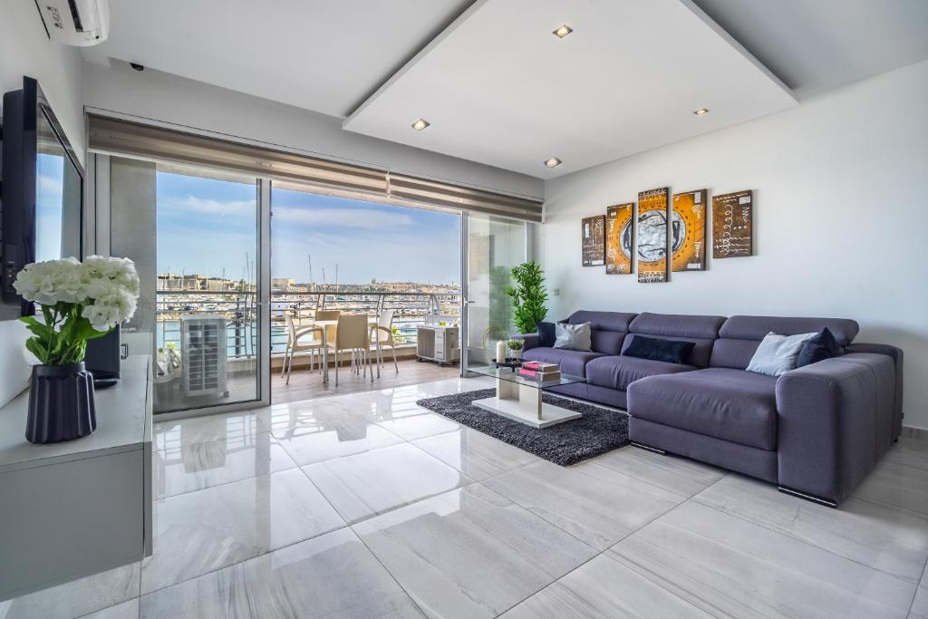 ein Wohnzimmer mit einem lila Sofa und einem Tisch in der Unterkunft Large & Modern 2BR Seafront Apartment with Large Balcony - Close to Saint Julian's, Sliema, & Manoel Island in Gżira
