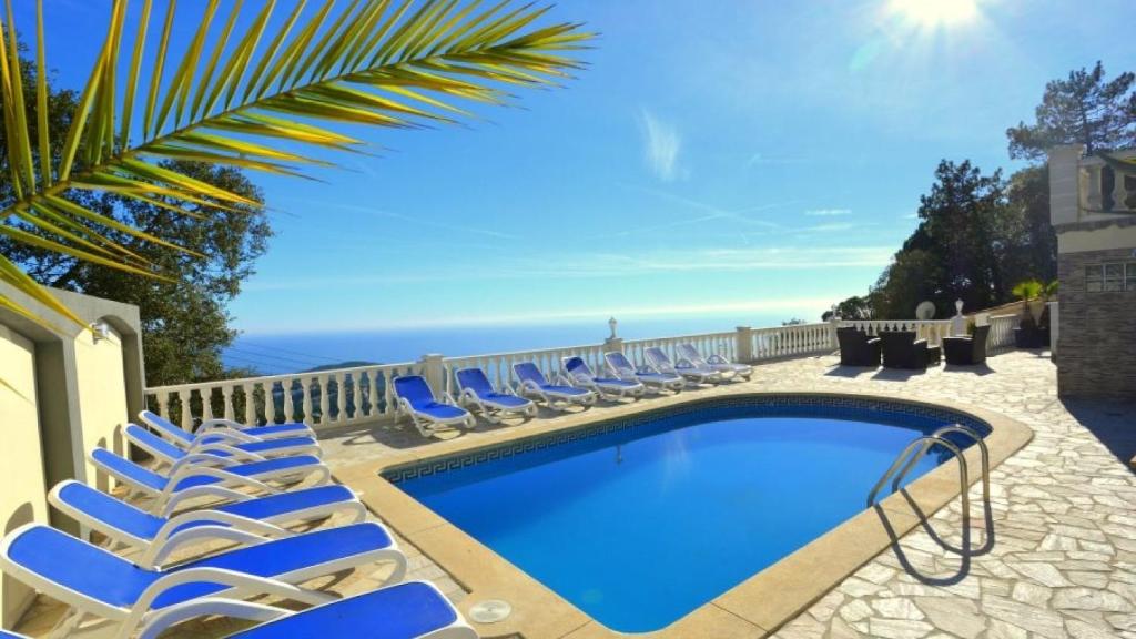 - une piscine avec des chaises longues et l'océan dans l'établissement Costacabana - Villa Promessa, à Lloret de Mar