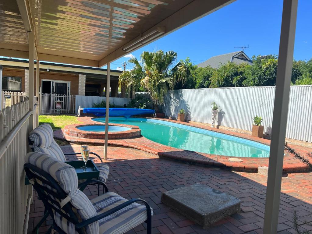a patio with a pool with chairs and a table at Shazza’s Desert Oasis in Broken Hill