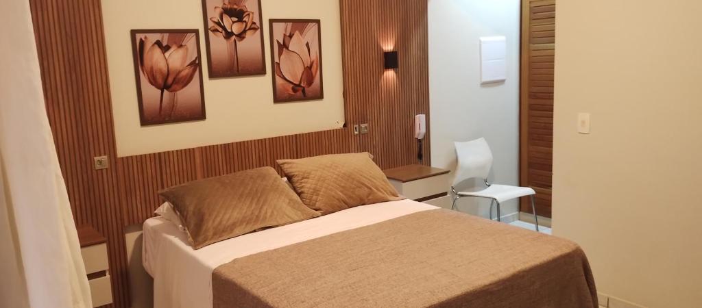1 dormitorio con 1 cama y pinturas en la pared en RIVIERA SERVICE- Suíte Casal -113 en Bertioga